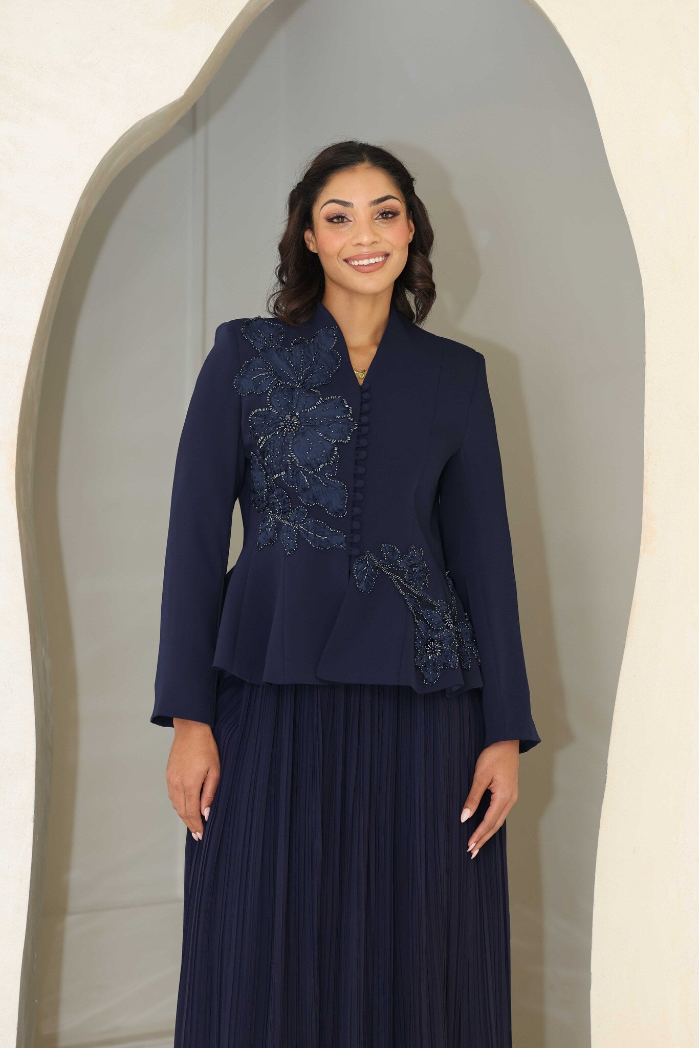 Navy blue pleated midi dress with floral appliqué and beaded detailing on the bodice.