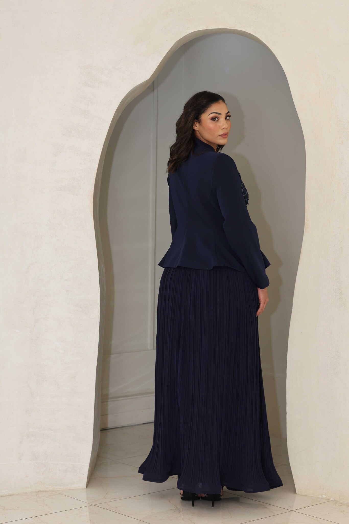 Navy blue pleated midi dress with floral appliqué and beaded detailing on the bodice.