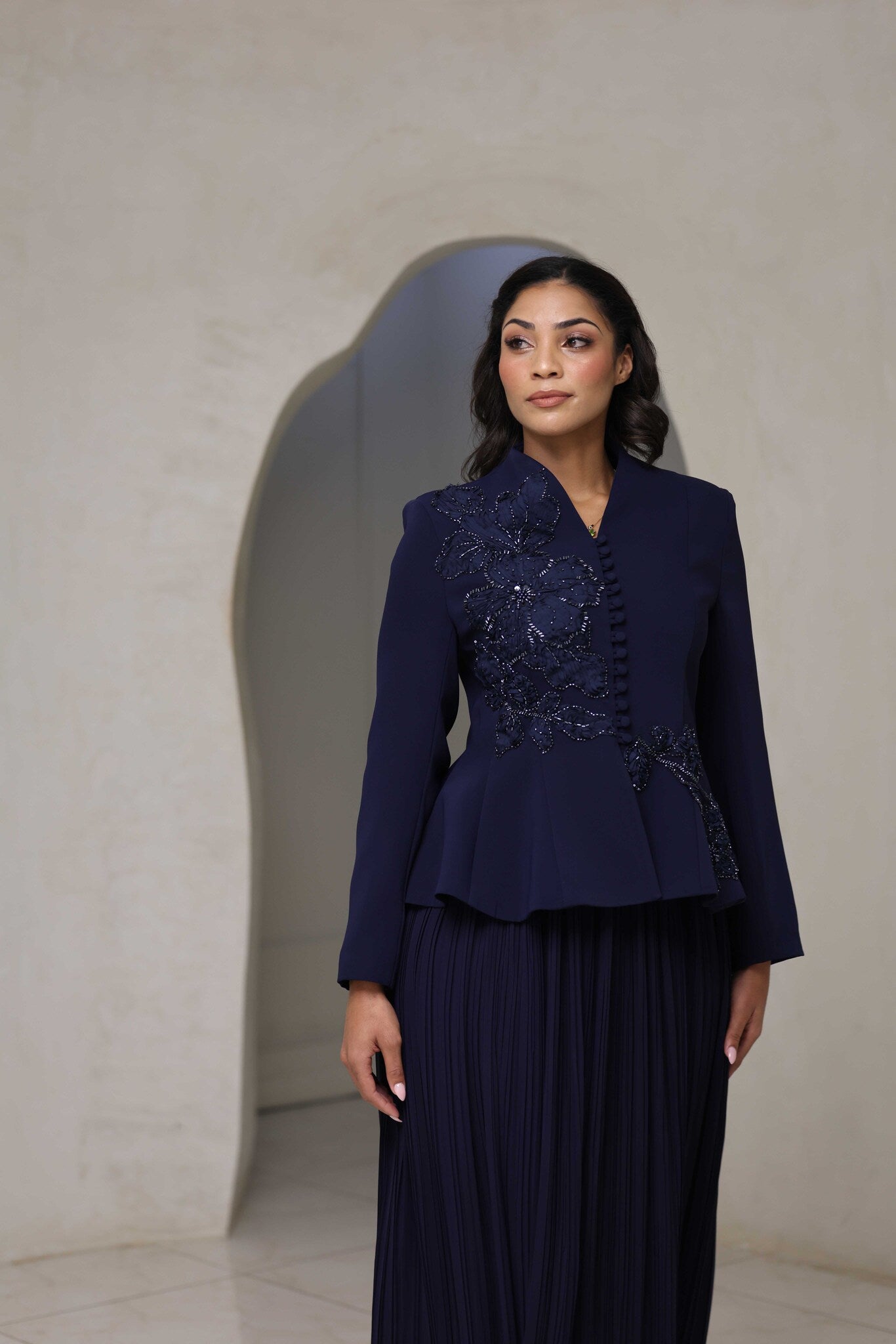 Navy blue pleated midi dress with floral appliqué and beaded detailing on the bodice.