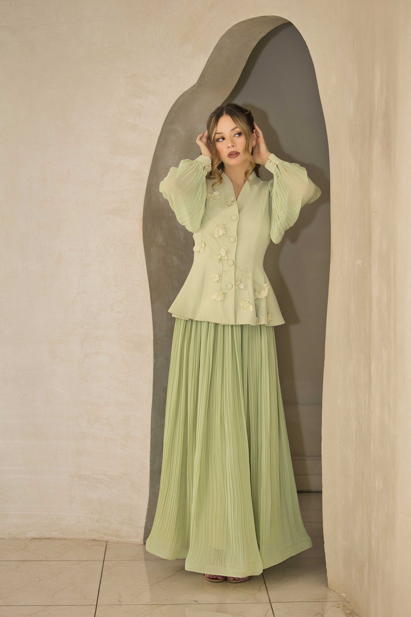 Pistachio green pleated dress with floral appliqué and hand-beaded detailing on the bodice.