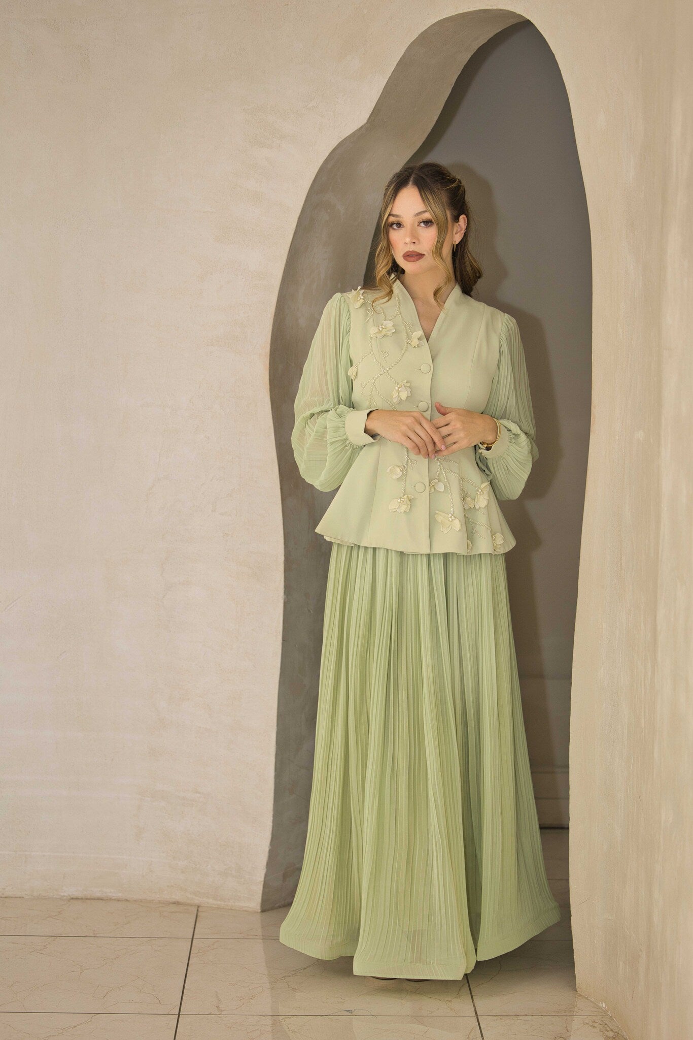 Pistachio green pleated dress with floral appliqué and hand-beaded detailing on the bodice.