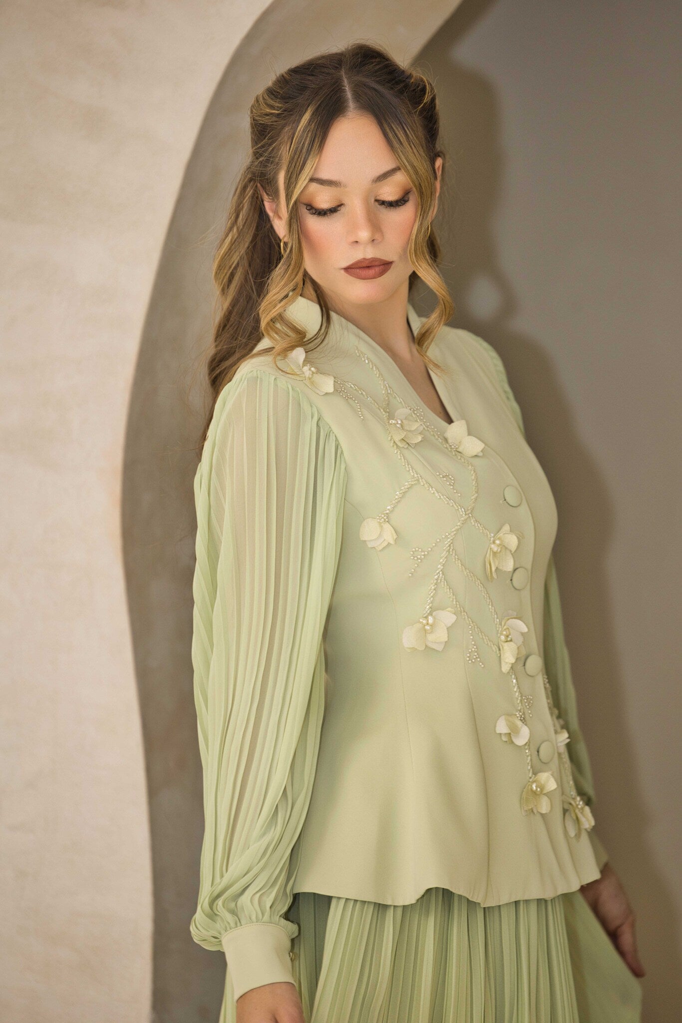 Pistachio green pleated dress with floral appliqué and hand-beaded detailing on the bodice.