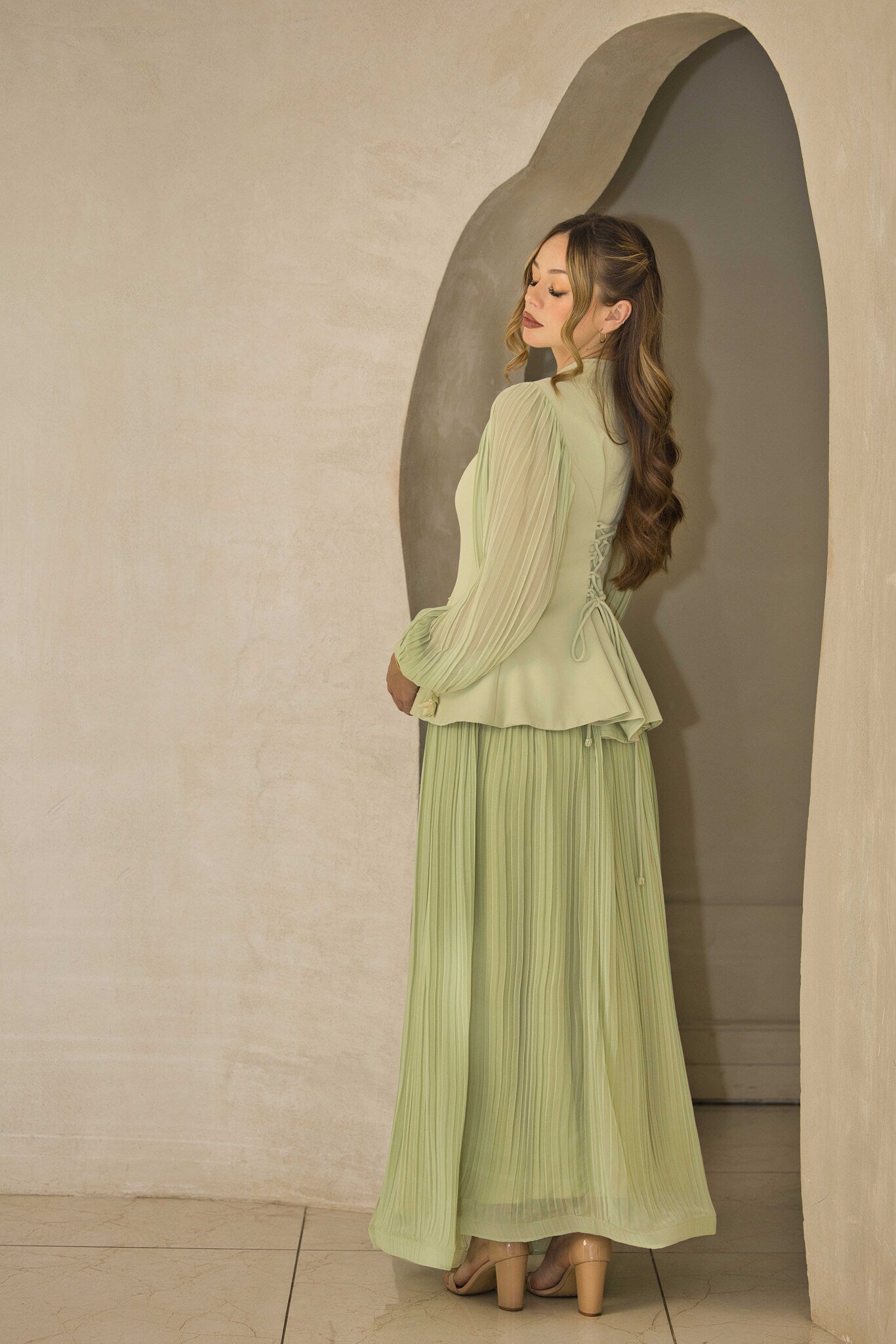 Pistachio green pleated dress with floral appliqué and hand-beaded detailing on the bodice.